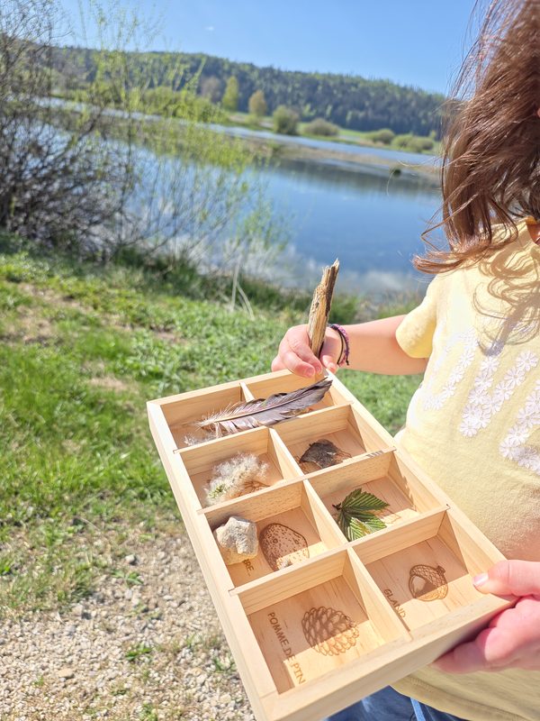 Enfant complétant sa boîte avec une brindille